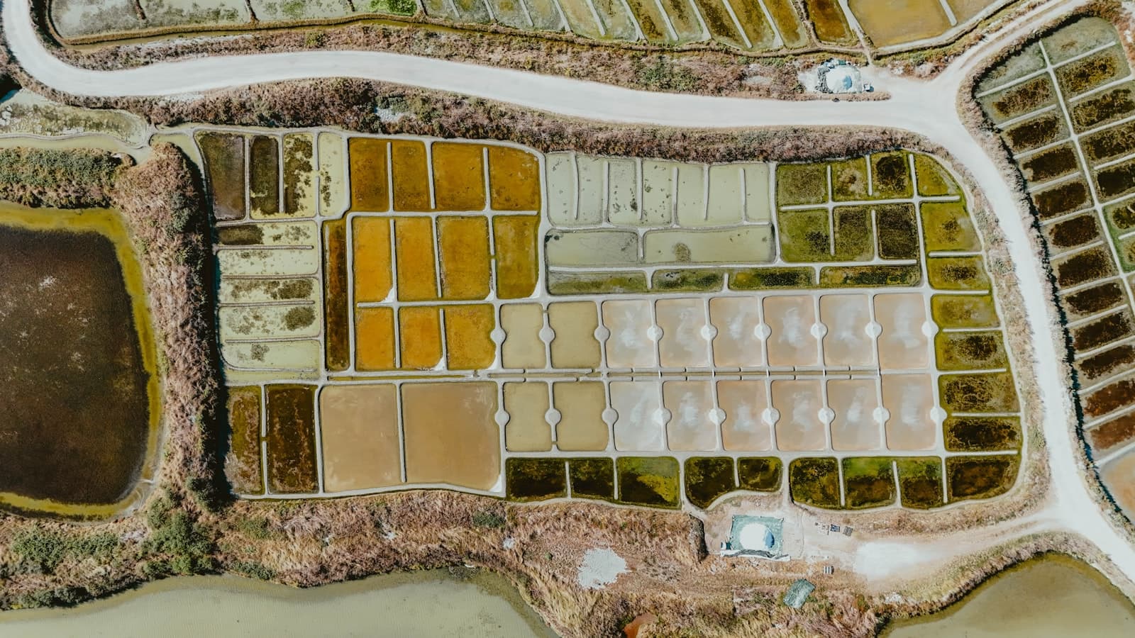 Aerial view of brine evaporation ponds in ochre and green tones, the kind of concentrate management infrastructure the collaboration focuses on