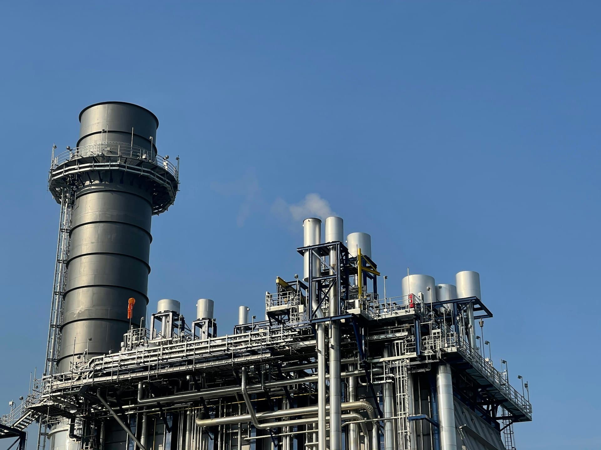 Industrial plant with tall exhaust stack and air-handling structures used for stripping volatiles from water