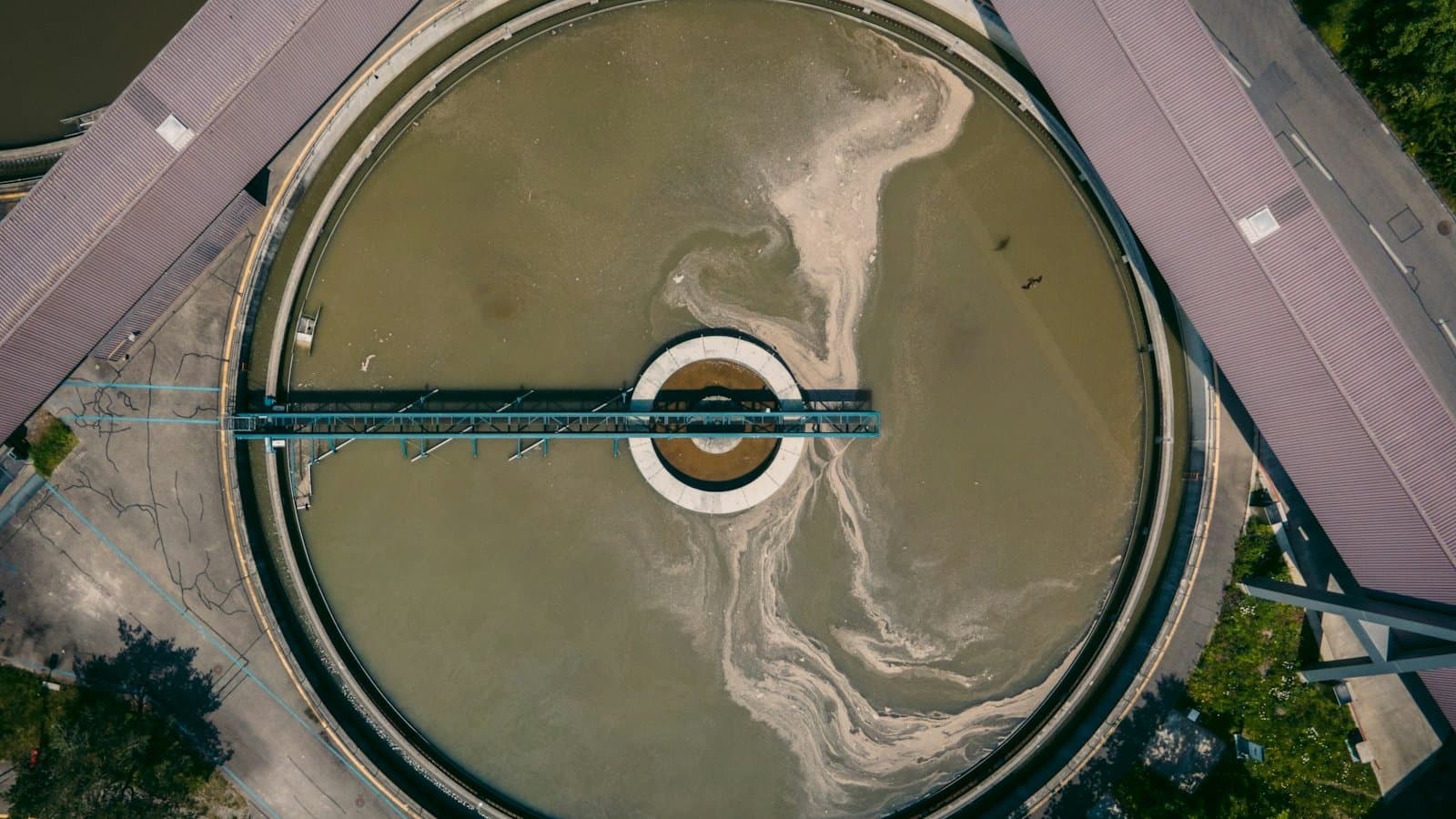 Aerial view of an industrial wastewater treatment clarifier with circular sedimentation tank and surrounding process infrastructure, representing the coagulation-flocculation stage of industrial wastewater plants