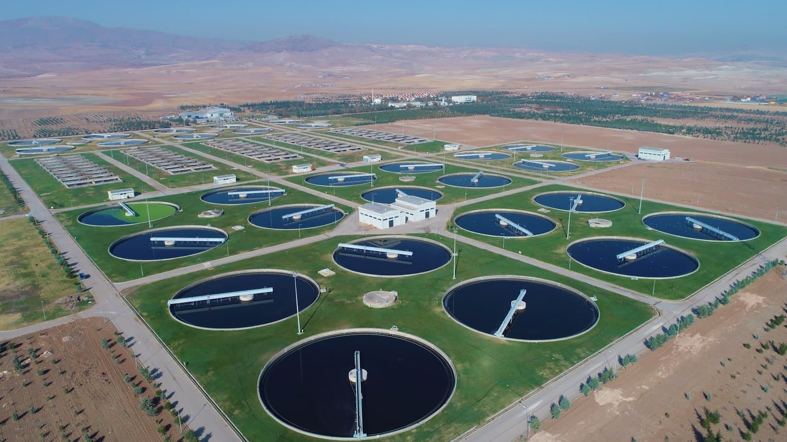 Aerial view of a large field of industrial water storage tanks, illustrating the scale differences between open, closed, and hybrid cooling tower configurations