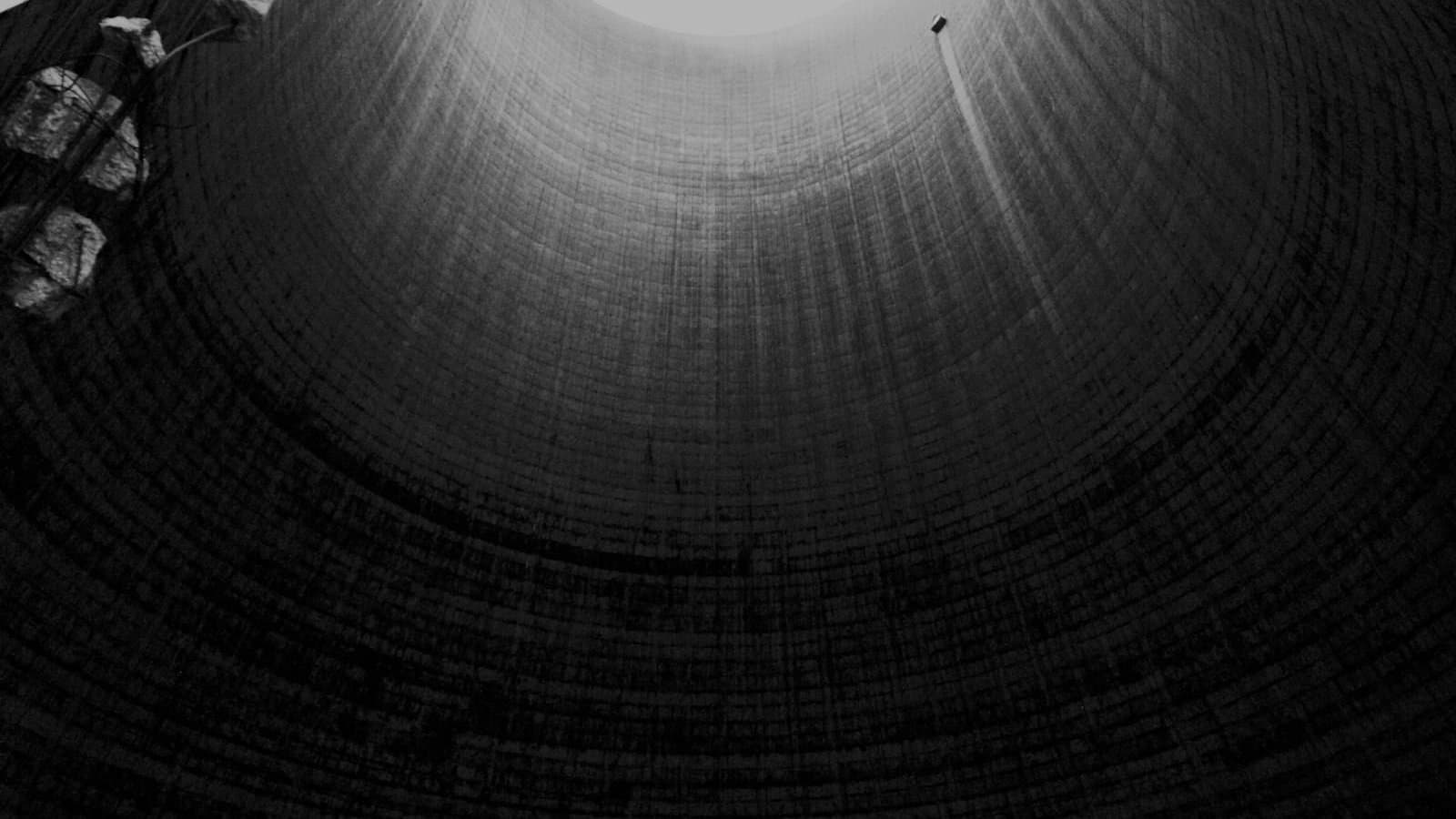 Inside view of a large decaying industrial cooling tower showing the concrete hyperbolic structure