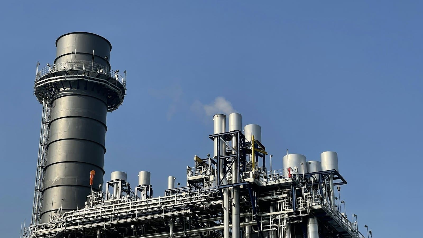 Gray and black industrial factory under a blue sky, an evaporative cooling tower plant where heat is rejected through water phase change to atmosphere