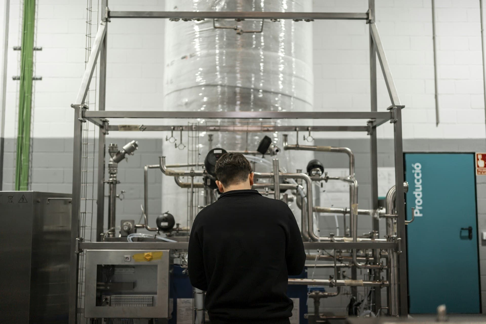Engineer inspecting a stainless buffer vessel in an industrial chilled-water plant