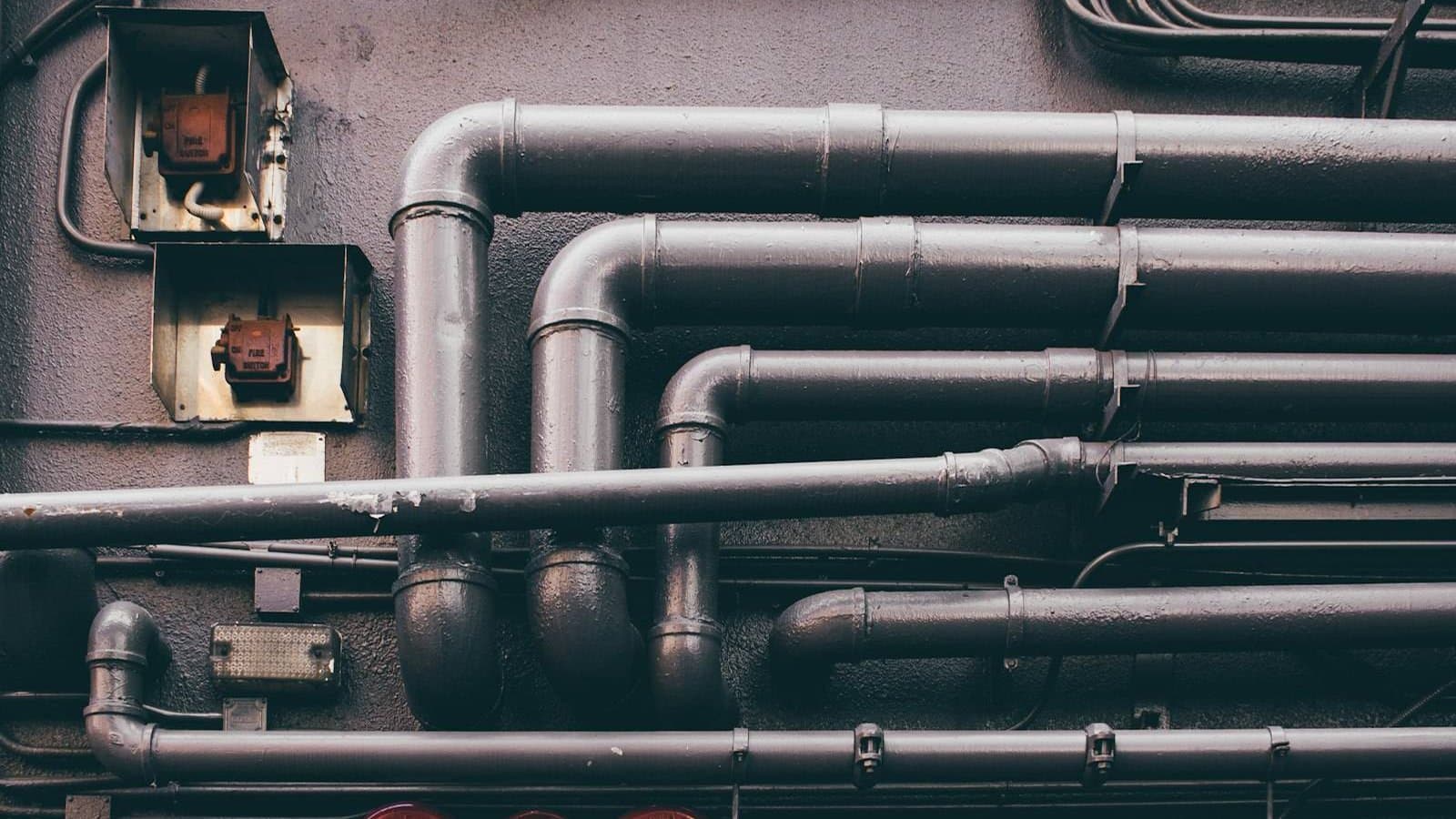 Rows of black metal tubes stacked in an industrial setting, the pipe and vessel array typical of multi-media filtration and activated carbon filter systems