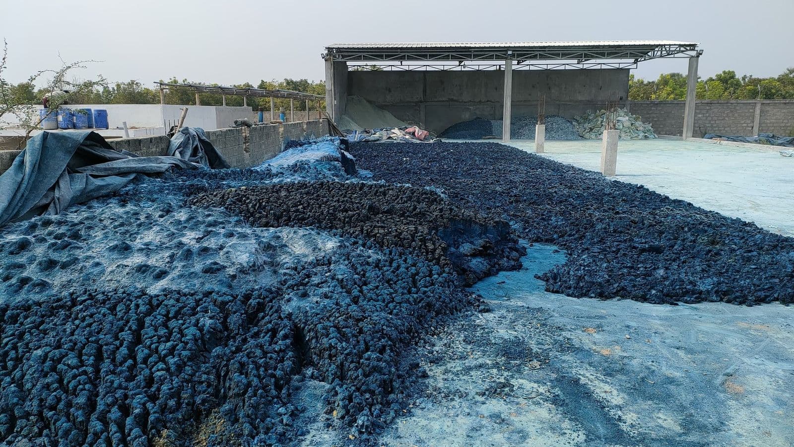 Dye-stained textile sludge spread across open drying beds — the visible footprint of untreated industrial discharge