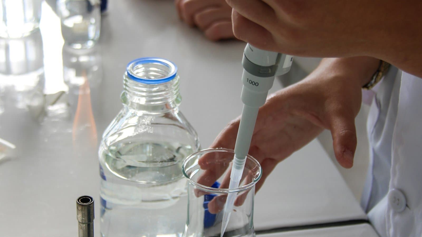 Pipette and glass bottles of purified water on a pharmaceutical laboratory bench