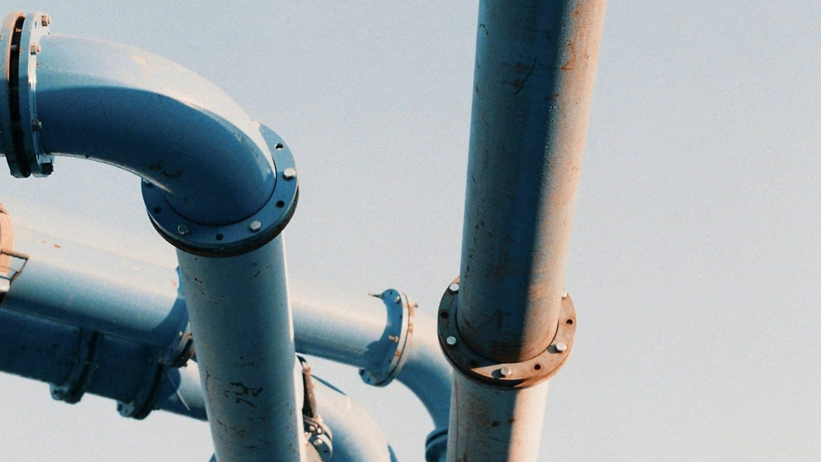 Blue and white metal pipe infrastructure in an industrial water treatment system, the high-pressure pipework characteristic of reverse osmosis membrane arrays