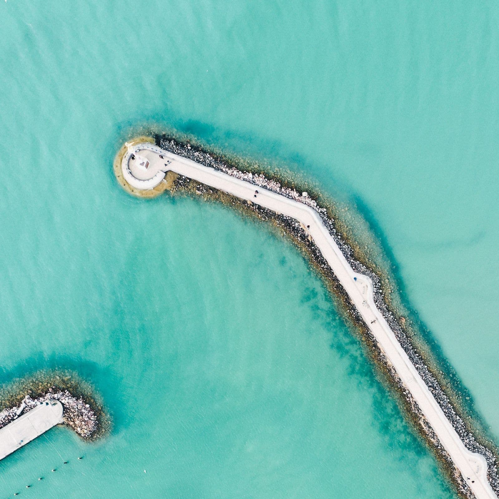 Aerial view of a breakwater reaching into turquoise seawater — the intake territory of seawater desalination