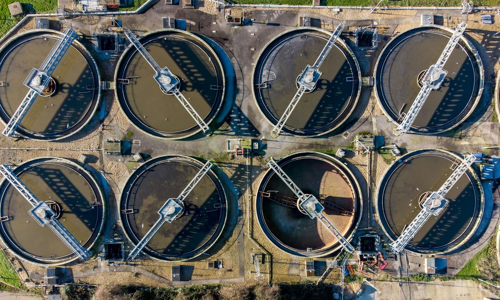 Aerial view of circular treatment basins — capital-intensive infrastructure whose cost profile is fixed at the design stage