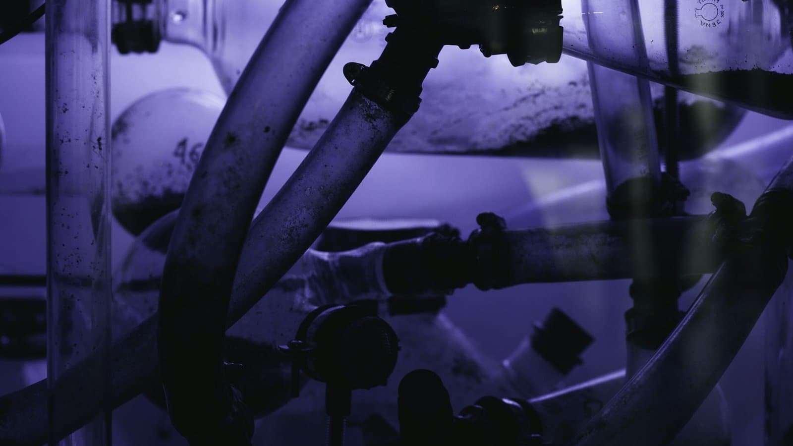 Dense array of industrial pipes and fittings in a process plant room, the distribution infrastructure through which water treatment chemicals are dosed and controlled
