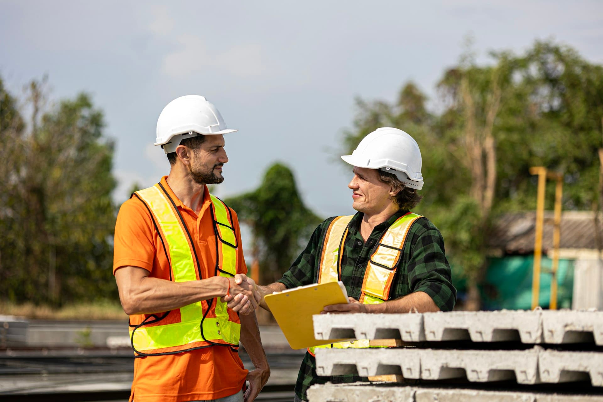 Two engineers in hard hats reviewing documentation together on site
